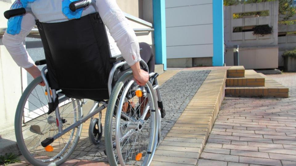 Ein Rollstuhlfahrer nutzt eine Rampe in ein Gebäude